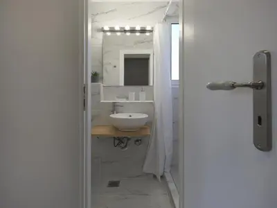 a white bathroom with a sink and a mirror at Acropolis View top floor apartment in Athens