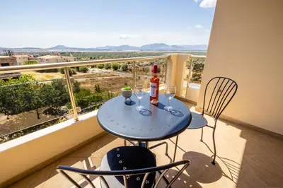 a table with two glasses of wine on a balcony at Thea Apartment_Athens Airport in Spáta
