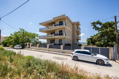 a white car parked in front of a building at Thea Apartment_Athens Airport in Spáta