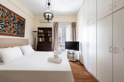 a white bedroom with a white bed and a tv at All time Classic: Pianist's 5th FL Apt @ Acropolis in Athens
