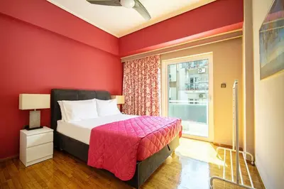 a red bedroom with a bed and a window at Μοντέρνο διαμέρισμα 2' από το μετρό in Athens