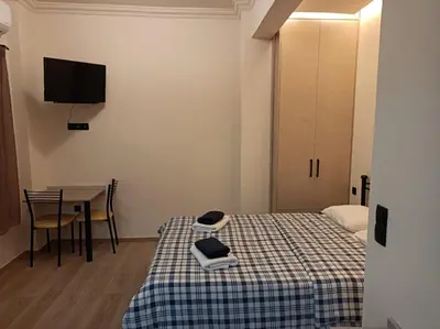 a room with two beds and a table and a tv at Apartment Dipla in Athens