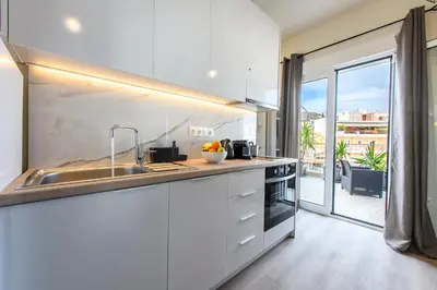 a white kitchen with a sink and a large window at Beautiful loft close to Acropolis in Athens