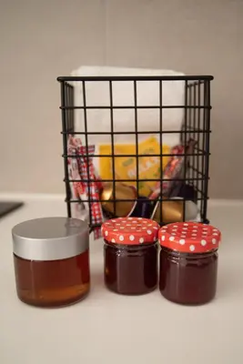 three jars of honey next to a cage with a bird at Naiads Nest - The Blue Wave in Varkiza
