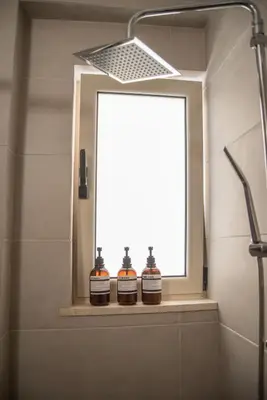 two bottles of whiskey sitting on a window sill in a bathroom at Naiads Nest - The Blue Wave in Varkiza