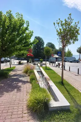a brick sidewalk with grass and trees on a street at Naiads Nest - The Blue Wave in Varkiza