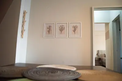 a table with three pictures on the wall and a plate at Naiads Nest - The Cozy Retreat in Varkiza