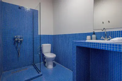 a blue tiled bathroom with a toilet and a sink at Cream in Athens