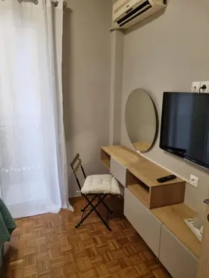 a room with a tv and a mirror and a chair at Piraeus open view Appartment in Piraeus