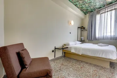 a bedroom with a bed and a chair and a window at 7ATHENS in Athens