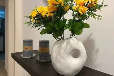a white vase with yellow flowers on a table at Pame Rentals - Ideal For 4 in Pagrati in Athens