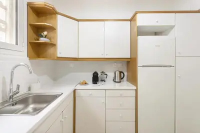 a white kitchen with a sink and a refrigerator at Pausaniou8 in Athens