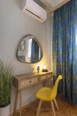 a dressing table with a yellow chair and a mirror at Pausaniou8 in Athens