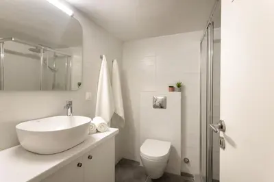 a white bathroom with a sink and a toilet at Pausaniou8 in Athens