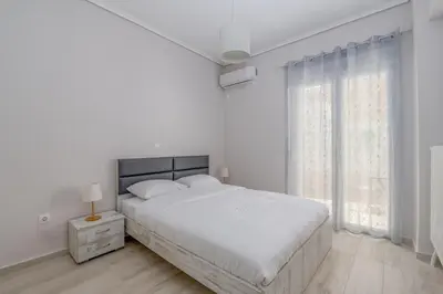 a white bedroom with a large bed and a window at Marina Zeas Hidden Gem in Piraeus