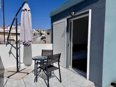a chair and a table on a balcony with an umbrella at Athenian Sky in Athens