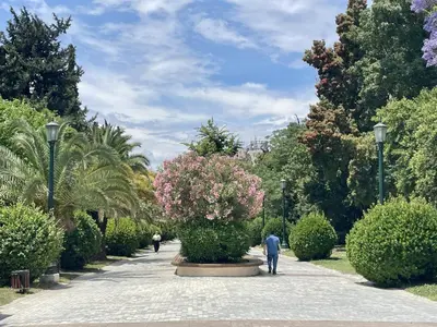a man walking through a park with a flower bush at Comfortable apartment next to Museum and park in Athens