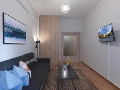 a living room with a black couch and a table at Comfortable apartment next to Museum and park in Athens