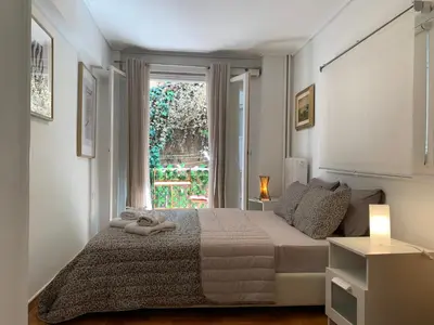 a white bedroom with a bed and a window at Chic Urban Living: Apartment in Acropolis-Koukaki in Athens