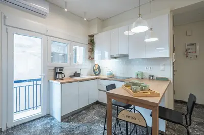 a kitchen with white cabinets and a wooden table at The Luxury Suite by Cloudkeys in Athens