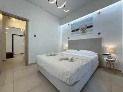 a white bedroom with a large bed and a mirror at 'Η Ωραία των Αθηνών' A Lux & Cozy Apt in Athens in Athens