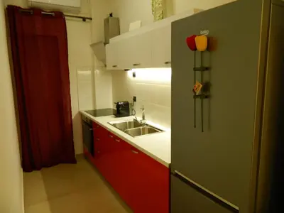 a small kitchen with red cabinets and a sink at 'Η Ωραία των Αθηνών' A Lux & Cozy Apt in Athens in Athens
