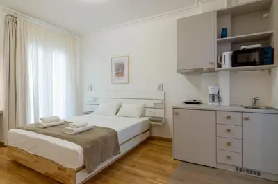 a white bedroom with a bed and a kitchen at Exclusive Studio in Athens A in Athens