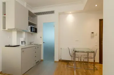 a kitchen with white cabinets and a table and a refrigerator at Exclusive Studio in Athens A in Athens