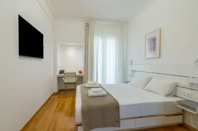 a white bedroom with a large bed and a desk at Exclusive Studio in Athens A in Athens