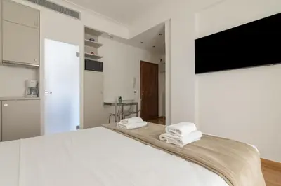 a white bedroom with a bed and a flat screen tv at Elegant Studio In Athens B in Athens