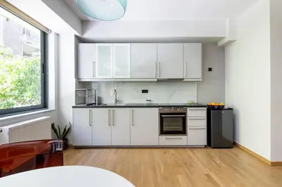 a kitchen with white cabinets and a black refrigerator at Bright 2BDR Apartment Downtown Exarcheia! in Athens