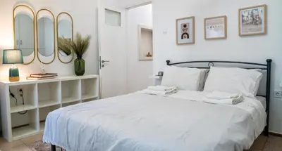 a bedroom with a bed with white sheets and mirrors at Lux Garden Apartment near Acropolis in the heart of Athens in Athens