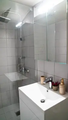 a bathroom with a sink and a shower with a mirror at Lux Garden Apartment near Acropolis in the heart of Athens in Athens