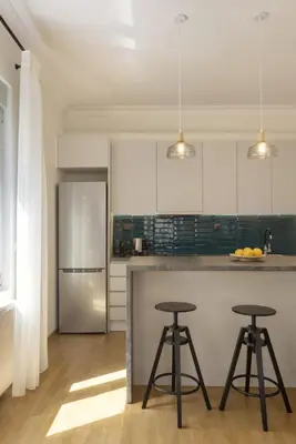 a kitchen with white cabinets and two bar stools at Versi2- Stylish 1BR pays homage to timeless charm in Athens