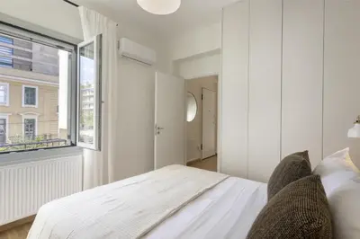 a bedroom with a white bed and a window at Versi2- Stylish 1BR pays homage to timeless charm in Athens