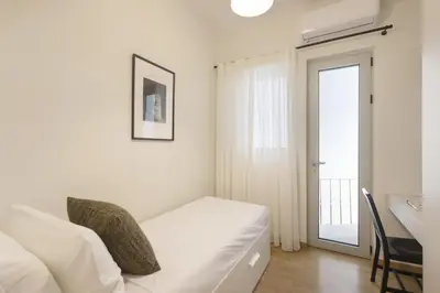 a white bedroom with a white couch and a window at Versi2- Stylish 1BR pays homage to timeless charm in Athens