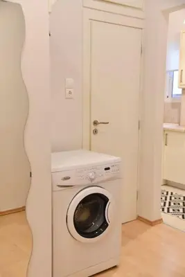 a washer and dryer in a white room at Tiny Treasure Apartment in Athens