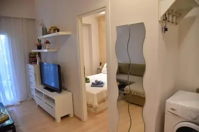 a room with a bedroom with a mirror and a television at Tiny Treasure Apartment in Athens
