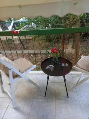 a table and a chair and a vase of flowers on a balcony at Tiny Treasure Apartment in Athens