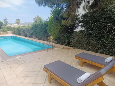 a swimming pool with two benches next to at Sunset Sea Mini Studio Anavissos in Anavissos