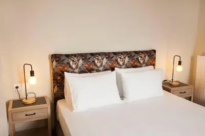 a bedroom with a white bed with two night stands at Pagrati Hilton location Bentzi Family Suite 5 in Athens