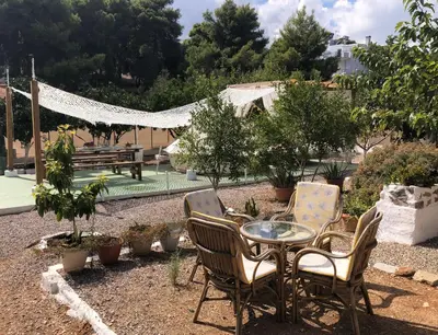 a patio with a table and chairs in a yard at Camping Tent Downtown & Garden Hanging Bed in Porto Rafti