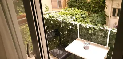 a balcony with a white table and a green hedge at Luxury apartment 3 rooms near metro in Athens