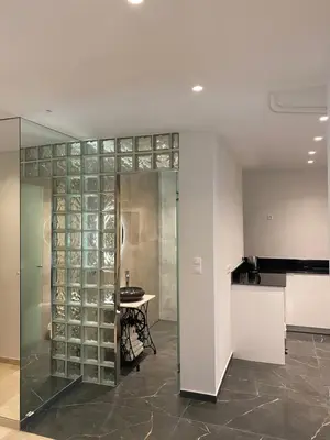 a glass wall in a room with a table and a kitchen at Marina Access in Athens