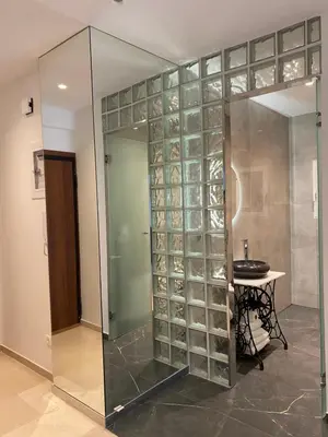 a glass walled shower in a room with a table at Marina Access in Athens