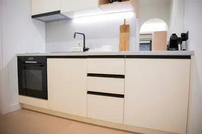 a white kitchen with a sink and a stove at G&H Acropolis Stays! Iconic Views, Stylish Comfort in Athens