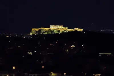 a building on top of a hill at night at Alex Suite Θερμαινόμενο Τζακούζι & Θέα Ακρόπολη in Athens
