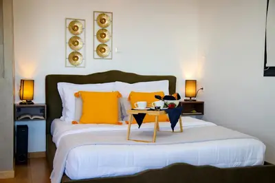a bedroom with a bed with orange pillows and a table at Alex Suite Θερμαινόμενο Τζακούζι & Θέα Ακρόπολη in Athens