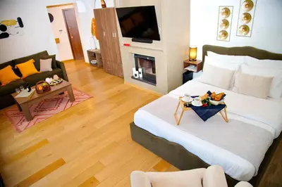 a bedroom with a large bed and a living room at Alex Suite Θερμαινόμενο Τζακούζι & Θέα Ακρόπολη in Athens