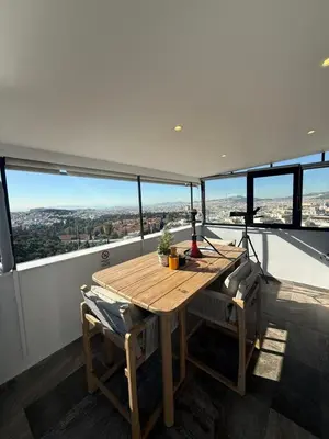 a wooden table and two chairs on a balcony at Alex Suite Θερμαινόμενο Τζακούζι & Θέα Ακρόπολη in Athens